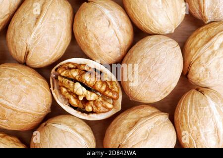 top view of shelled walnut between walnuts in shell background pattern Stock Photo