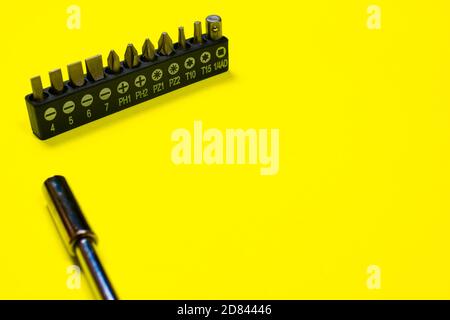 A set of screwdriver nozzles and a screwdriver on a yellow background with space for copyspace text. Tools for construction and repair shop. Stock Photo