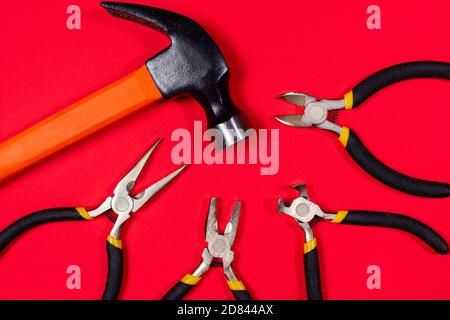 Construction tools hammer, pliers, cutters. tongs and round-the-heads on a red background. Banner for construction store and repair. Stock Photo