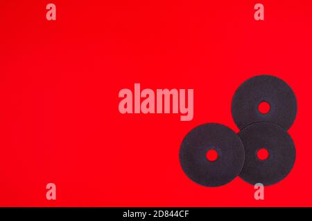 A cut-off wheel for a grinder tool on a red background with a place for copyspace text. Tools for construction and repair, workshop Stock Photo