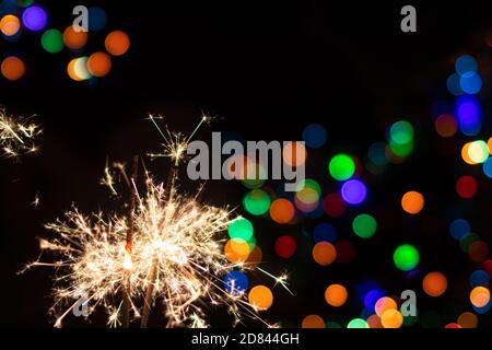 Sparkler on festive bokeh background. Festive greeting card for new year and christmas 2021, colorful lights in the background Stock Photo