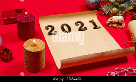 Parchment paper for the to-do list and text and a candle for the new year 2021 on a red background. Christmas, holiday card with plans for next year Stock Photo