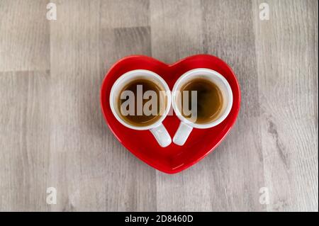 two cups of coffee with a red ceramic heart saucer Stock Photo