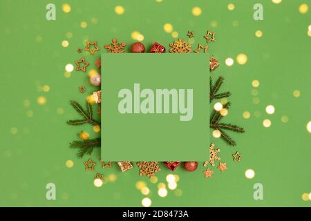 Green paper card with frame made of Christmas decorations and fir branches. Festive creative template. Stock Photo