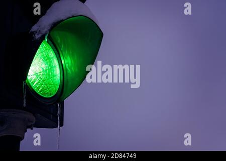 Green traffic lights covered in snow and icicle during blizzard and snowfall, Tromso, Norway Stock Photo