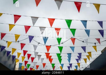 Colorful flags fluttering in the wind above the street market in the Catford Centre in Lewisham, London, UK Stock Photo