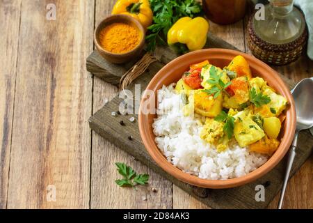 Indian cuisine dish sabji. Traditional Indian vegetable stew with soft cheese, turmeric and rice on a wooden table. Copy space. Stock Photo