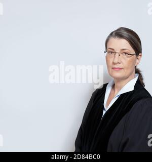 Portrrait of a middle aged female judge in black robe, neutral background, copyspace. Stock Photo