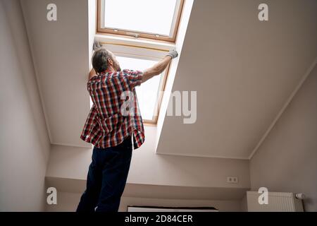 Repairman with measuring tape next to skylight window Stock Photo