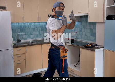 Young home master in face mask showing thumb up Stock Photo