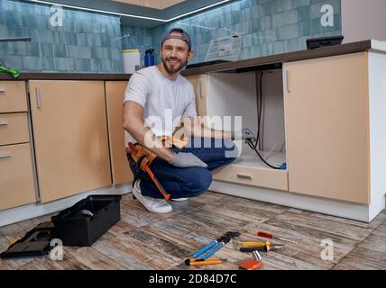 Young caucasian man working with wires on new kitchen Stock Photo