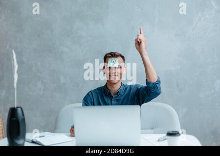 Satisfied man with raised hand thinking about good creative idea. Stock Photo