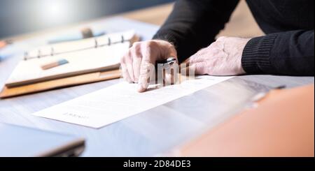 Senior businessman reviewing terms of contract at office Stock Photo