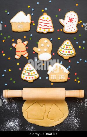 Christmas gingerbread cookies, rolling pin and dough on black background with confetti Stock Photo