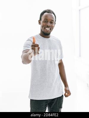 attractive young man in white t-shirt showing thumbs up. Stock Photo