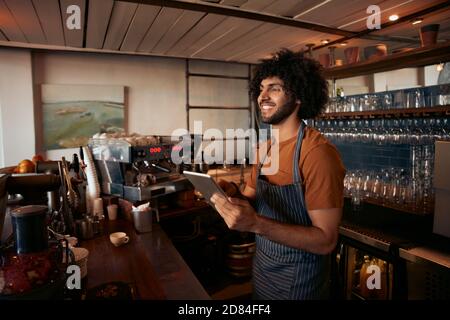 Smiling male entrepreneur in his coffee shop holding digital tab Stock Photo