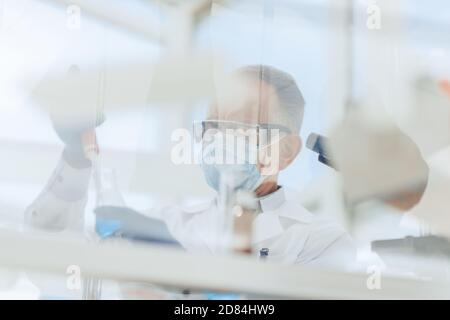 scientist sitting using an automatic dispenser for his research. Stock Photo