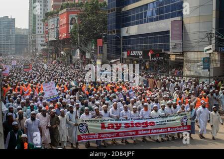 Muslim protesters hold a large banner during the protest march against French president Emmanuel Macron.The Islami Andolon, one of Bangladesh's largest Islamist parties, hold a protest march calling for the boycott of French products and denouncing French president Emmanuel Macron for his remarks ‘not to give up cartoons depicting Prophet Mohammed'. Macron's remarks came in response to the beheading of a teacher, Samuel Paty, outside his school in a suburb outside Paris earlier this month, after he had shown cartoons of the Prophet Mohammed during a class he was leading on free speech. Stock Photo