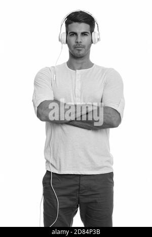 Young handsome Persian man listening to music with arms crossed Stock Photo