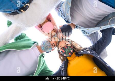 Multiracial millennial friends taking selfie smiling behind face masks - Happy friendship and new normal concept with young people having fun together Stock Photo