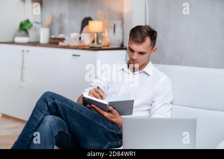 young man taking notes sitting on the couch . Stock Photo