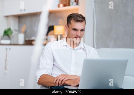 young man with a laptop is resting on the sofa . Stock Photo