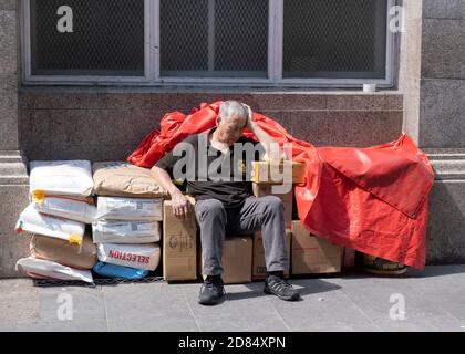 Old shopkeeper sitting and sleeping on his goods in Chinatown, London, England,Great Britain. Stock Photo