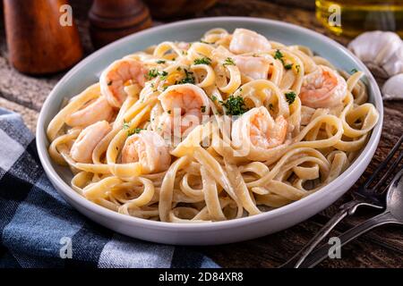 A plate of delicious shrimp alfredo with garlic and cream sauce over pasta. Stock Photo