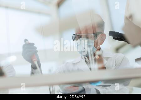 scientist sitting using an automatic dispenser for his research. Stock Photo