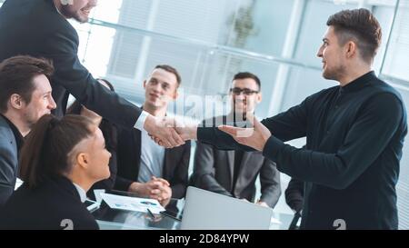 smiling business people shaking hands over an office Desk Stock Photo