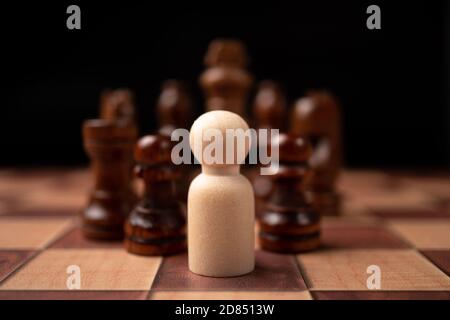 Wooden figures (businessman) standing confront of chess king and being in the chess circle. New business players are facing challenges. The management Stock Photo
