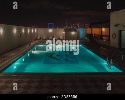 Night scene of a rooftop pool, lit-up and the beautiful Dubai skyline in the background. Stock Photo