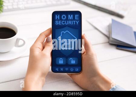 Lady using her smartphone with home security application Stock Photo