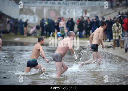 Group of people in swimsuits running out of icy water during the feast Epiphany on the Dnipro River. January 19, 2020. Kiev, Ukraine Stock Photo