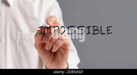 Businessman Crossing Out Word Impossible Making Everything Possible, Gray Background Stock Photo