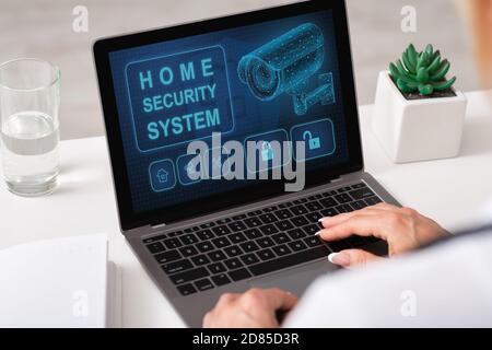 Woman using laptop with home security application Stock Photo
