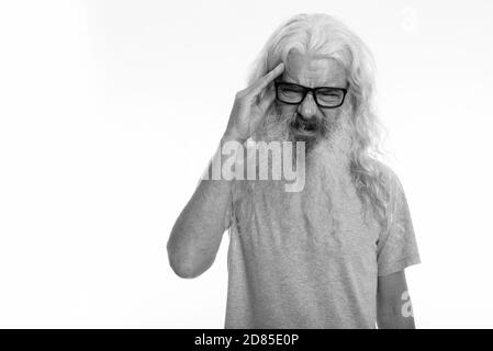 Studio shot of senior bearded man wearing eyeglasses while having headache Stock Photo