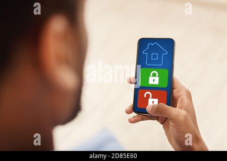 Man using his smartphone with home security application Stock Photo