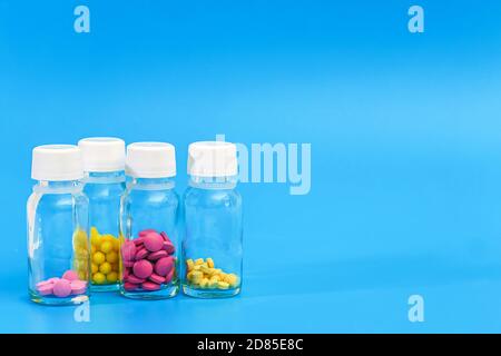 various pills in glass bottles on blue background with copy space Stock Photo