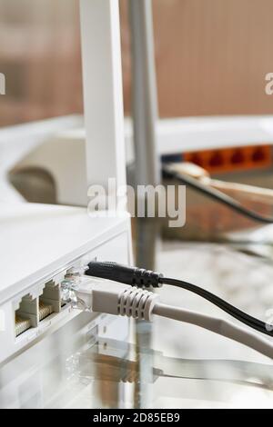 Two white wireless routers on a glass table connected by cables to the Internet. Close-up Stock Photo