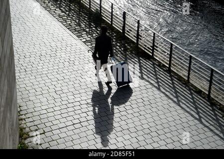 Berlin, Germany. 27th Oct, 2020. A man walks along the bank of the Spree with his suitcase. Credit: Kira Hofmann/dpa-Zentralbild/dpa/Alamy Live News Stock Photo