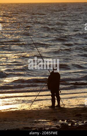 Croy Shore, Croy Bay, Carrick, Ayrshire, Scotland, UK.As the sunset over the Firth of Clyde on the West Coast of Scotland a fisherman sets his rod and line up for an evening of sea fishing. July 2012 Stock Photo