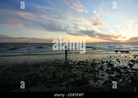 Croy Shore, Croy Bay, Carrick, Ayrshire, Scotland, UK.As the sunset over the Firth of Clyde on the West Coast of Scotland a fisherman sets his rod and line up for an evening of sea fishing. July 2012 Stock Photo