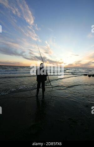 Croy Shore, Croy Bay, Carrick, Ayrshire, Scotland, UK.As the sunset over the Firth of Clyde on the West Coast of Scotland a fisherman sets his rod and line up for an evening of sea fishing. July 2012 Stock Photo