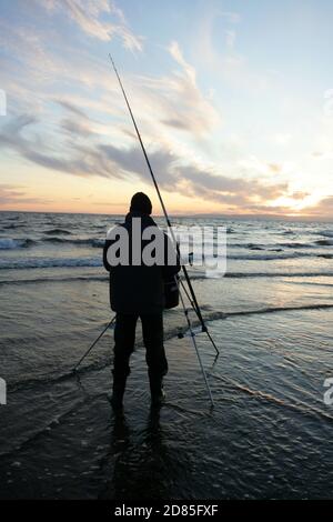 Croy Shore, Croy Bay, Carrick, Ayrshire, Scotland, UK.As the sunset over the Firth of Clyde on the West Coast of Scotland a fisherman sets his rod and line up for an evening of sea fishing. July 2012 Stock Photo