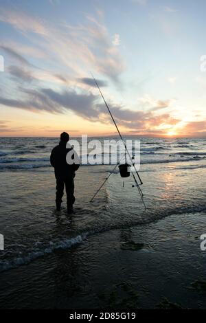 Croy Shore, Croy Bay, Carrick, Ayrshire, Scotland, UK.As the sunset over the Firth of Clyde on the West Coast of Scotland a fisherman sets his rod and line up for an evening of sea fishing. July 2012 Stock Photo