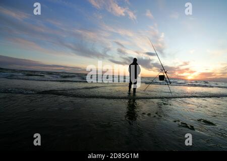 Croy Shore, Croy Bay, Carrick, Ayrshire, Scotland, UK.As the sunset over the Firth of Clyde on the West Coast of Scotland a fisherman sets his rod and line up for an evening of sea fishing. July 2012 Stock Photo