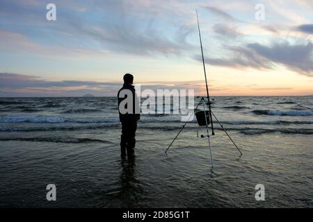 Croy Shore, Croy Bay, Carrick, Ayrshire, Scotland, UK.As the sunset over the Firth of Clyde on the West Coast of Scotland a fisherman sets his rod and line up for an evening of sea fishing. July 2012 Stock Photo