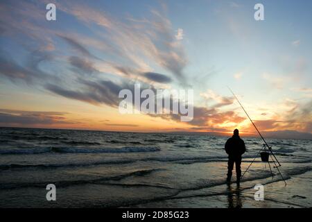 Croy Shore, Croy Bay, Carrick, Ayrshire, Scotland, UK.As the sunset over the Firth of Clyde on the West Coast of Scotland a fisherman sets his rod and line up for an evening of sea fishing. July 2012 Stock Photo