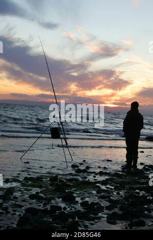 Croy Shore, Croy Bay, Carrick, Ayrshire, Scotland, UK.As the sunset over the Firth of Clyde on the West Coast of Scotland a fisherman sets his rod and line up for an evening of sea fishing. July 2012 Stock Photo